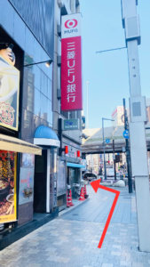 六本木交差点。東京タワーに向かう、外苑東通りの歩道。左側に水餃子店、交番。交番の看板の上に三菱UFJ銀行の大きな看板がある。