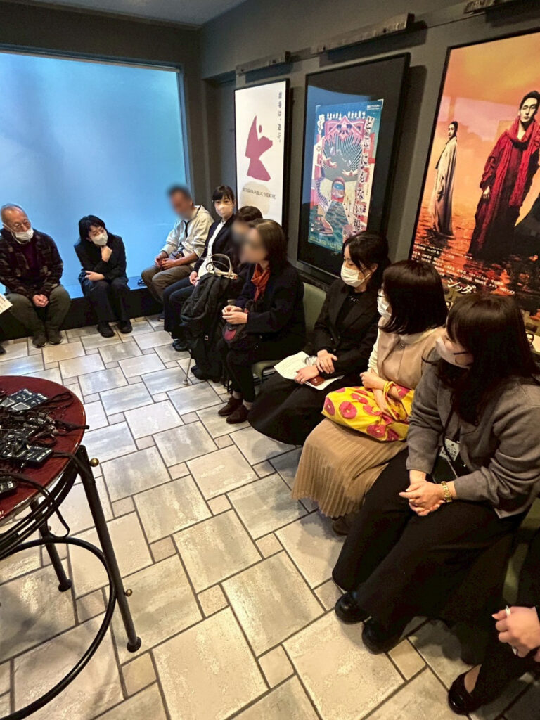 シアタートラムのロビーで、視覚障害の方さんにんを劇団員ろくにんがかこんでおはなしをきいています